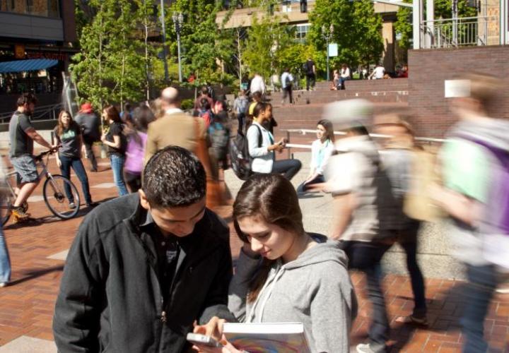 Two students in focus in a group of moving students outside