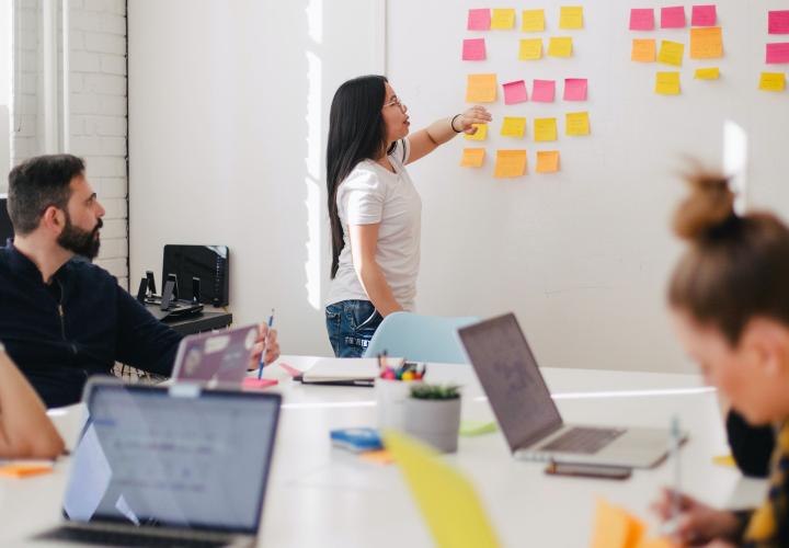 students putting post its on a white board in a classroom