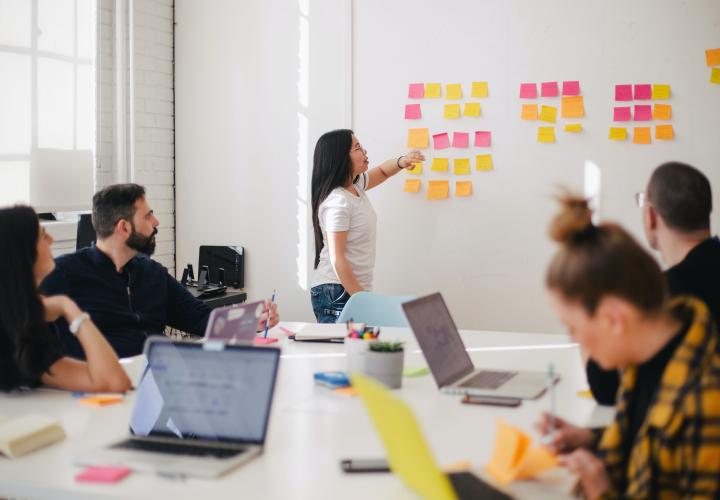 Students use sticky notes on a white board and have laptops open 