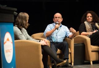 Panelists having a conversation on stage at the Elevating Impact Summit. 