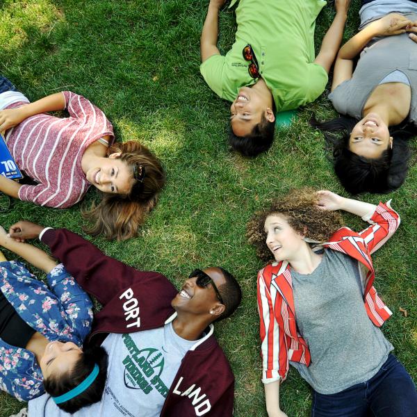 multiple students relaxing in the grass on the park blocks