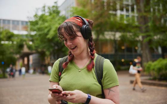 Student listening to headphones and exploring their phone