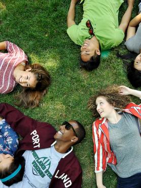 multiple students relaxing in the grass on the park blocks