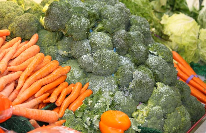 Produce such as carrots and broccoli laid out on a table.
