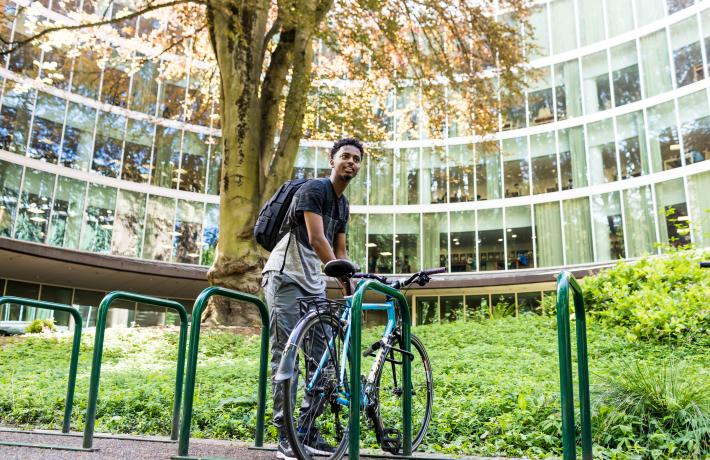 A student with their bike in front of the library.