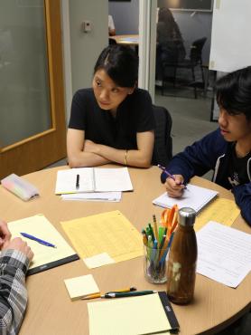 Two students at a table taking notes as they listen to an advisor.