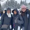 Three students stand in the snow smiling at the camera.