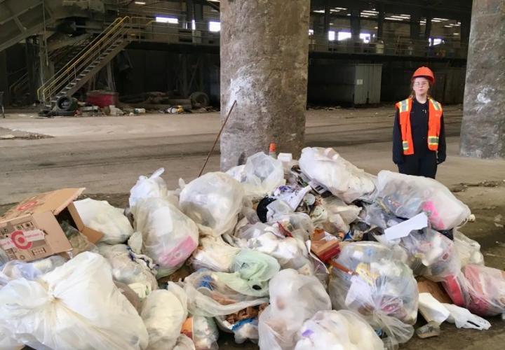 woman standing next to a pile of trash that was picked up