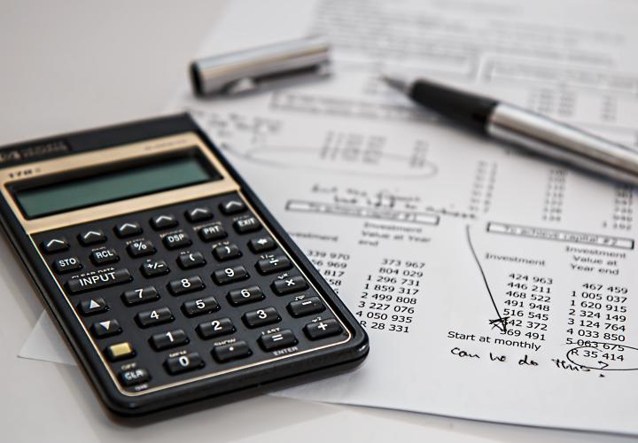 calculator and a pen laying on top of finance documents