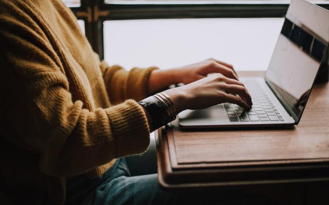 person sitting in front of a laptop and typing