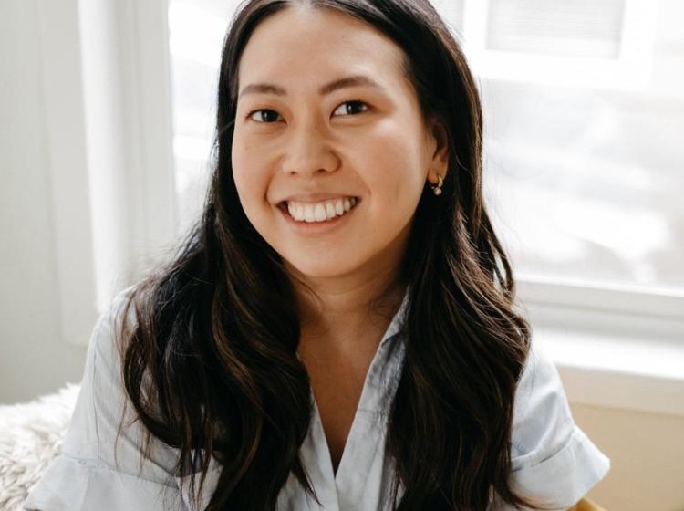 Photo of woman smiling into camera wearing a white blouse.