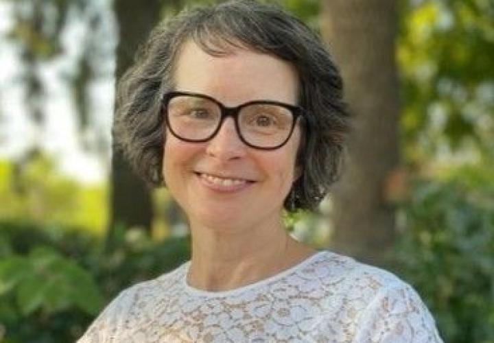 White woman smiling in glasses and white shirt