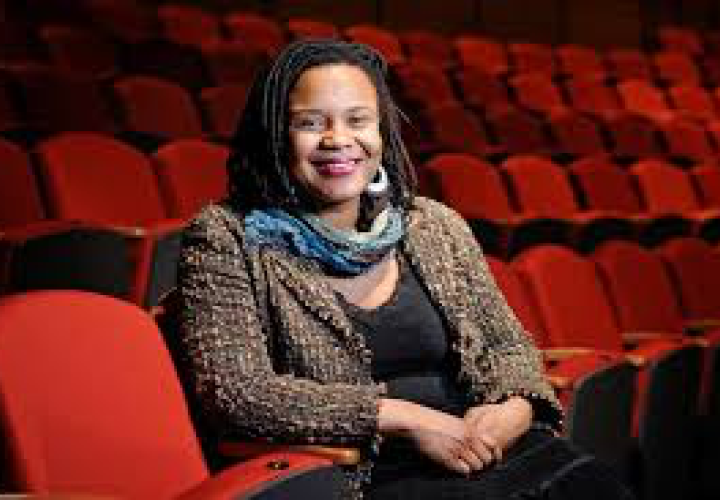 Black woman sitting in red theatre seat smiling
