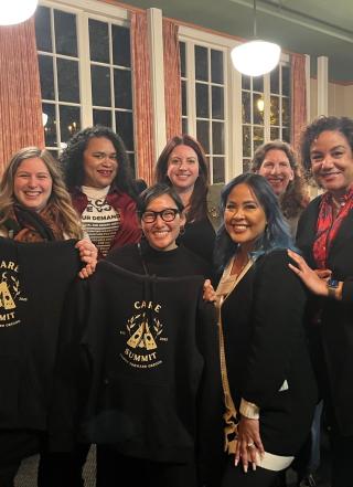 Care Summit organizers holding up conference sweatshirts and smiling 