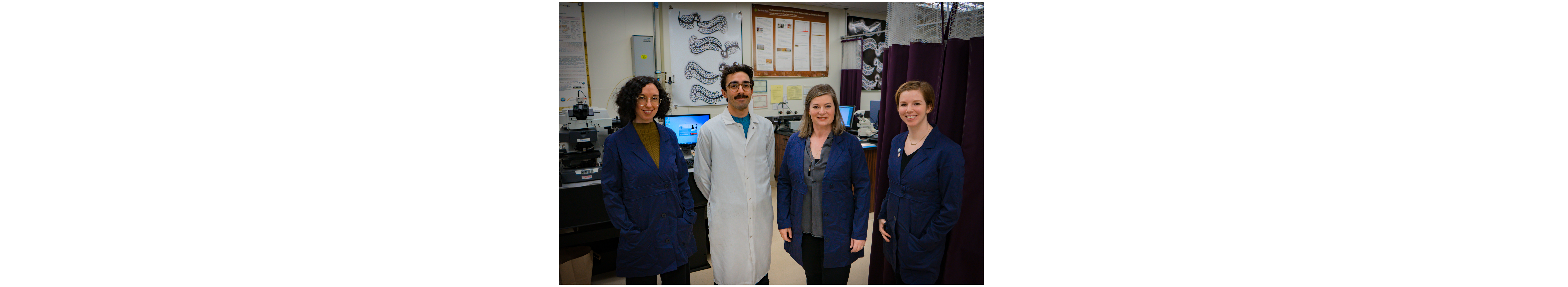 Four people in lab coats in a laboratory posing for the camera