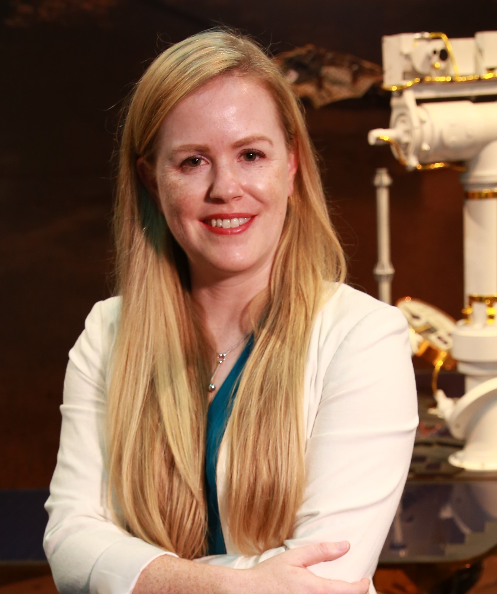 Laurie Barge, a white skinned woman with long blonde hair and wearing a white long sleeve cardigan, smiling at the camera