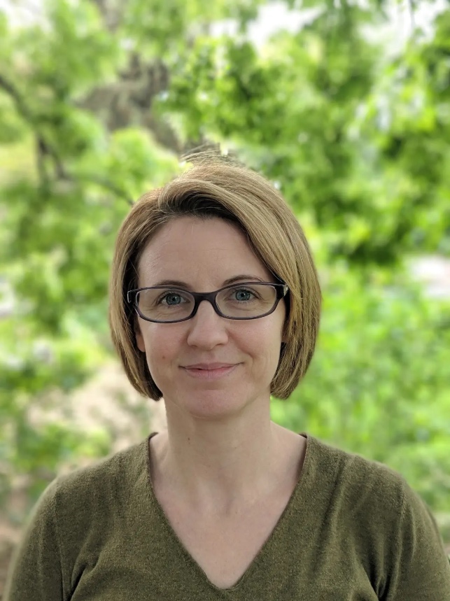 Professional head shot of Marilyne Stains, a white woman with short blonde hair and glasses.
