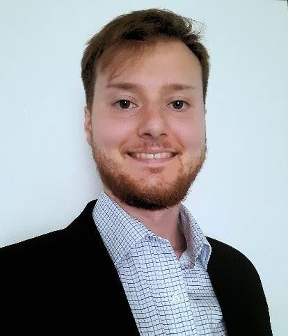 A headshot of Jake Nicholson, a white man with short red hair and beard. 