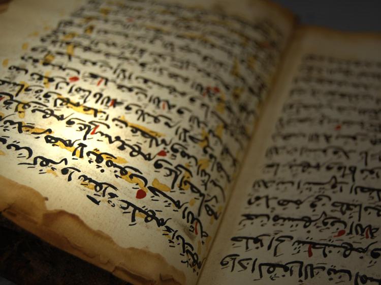 Book with text in arabic is shown open. Yellow and red markings are on the pages shown.