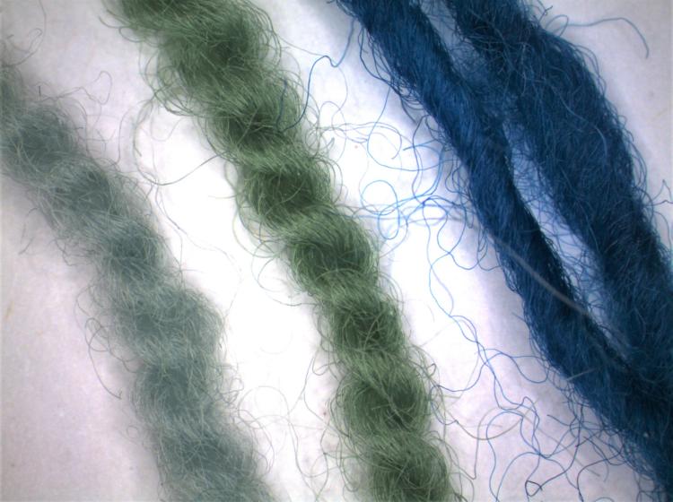 Three magnified fibers colored dark blue, green, and pale blue