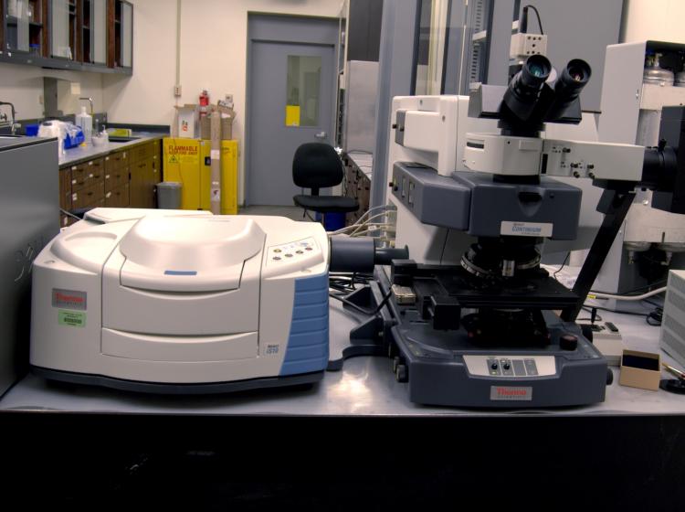 Microscope next to FTIR bench spectrometer in lab setting