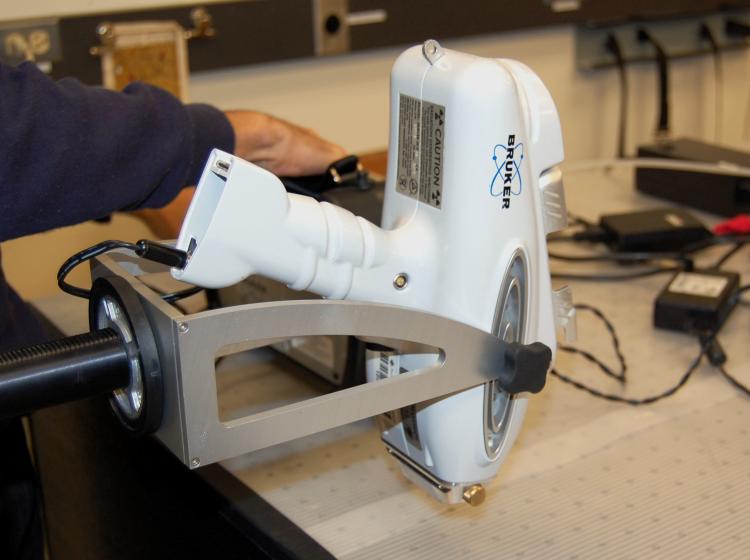 XRF instrument held in a positioning arm over a table