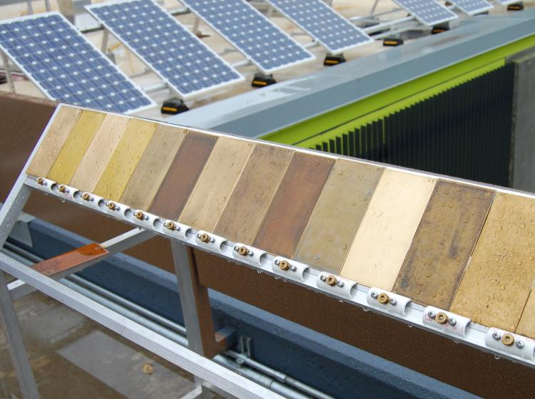 A long stand on a roof with rectangles of wet metal plates in a line on top