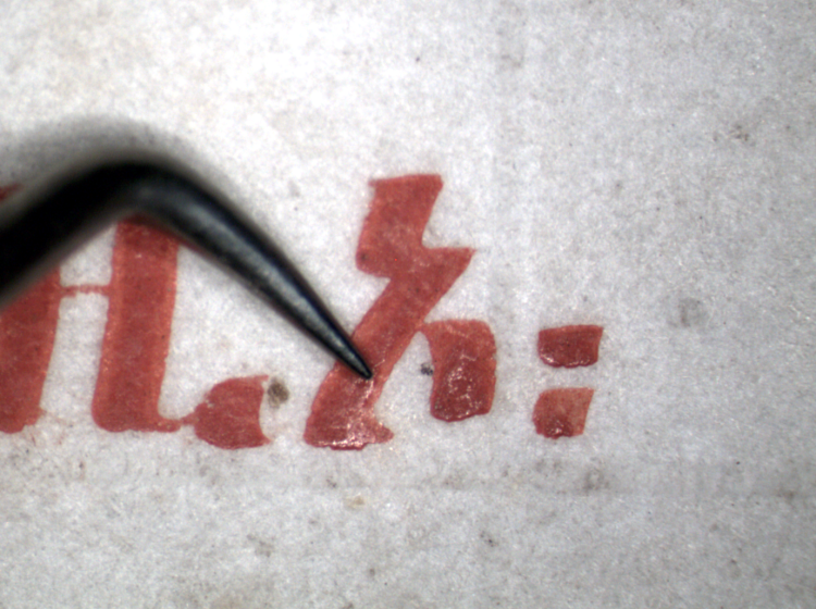 A magnified image of a metal probe touching a line of text