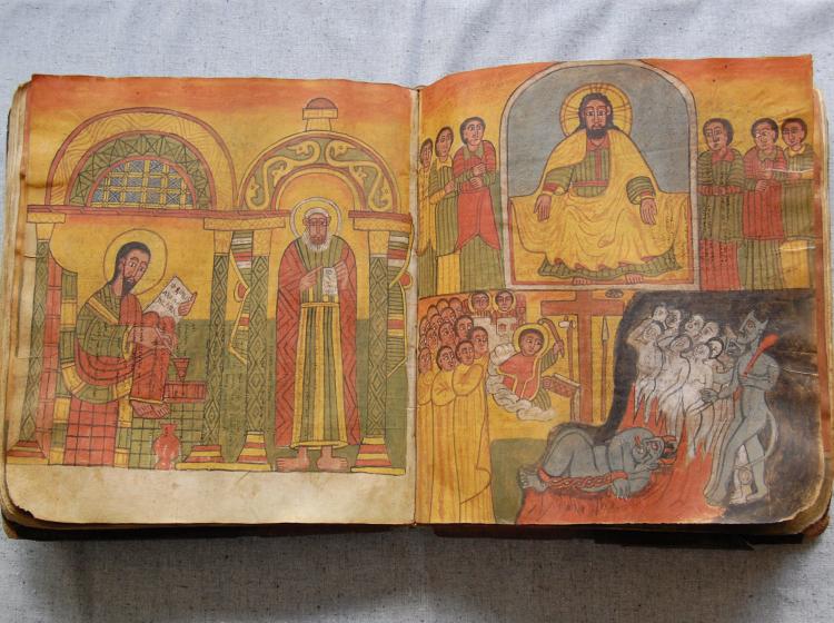 A manuscript open on a table to show two pages of richly colored religious imagery