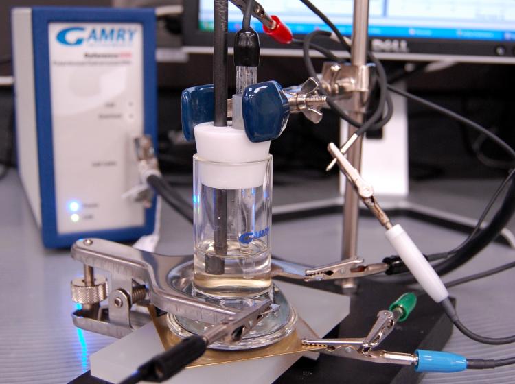 A vial of liquid clamped in place with electrical probes and clips attached