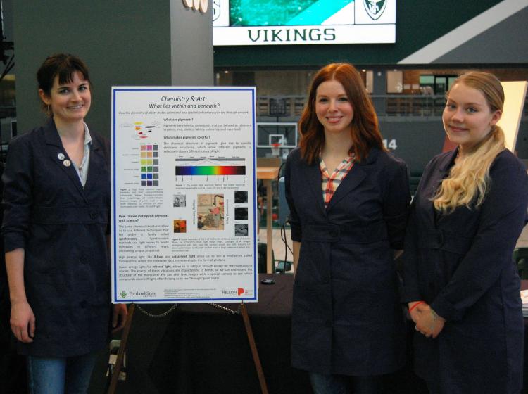 Three women standing beside a scientific poster