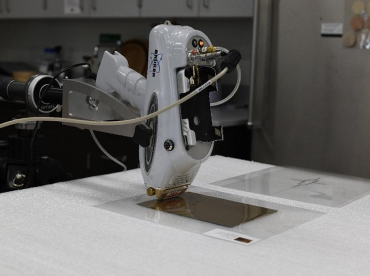 Handheld instrument suspended over a metallic plate on a table