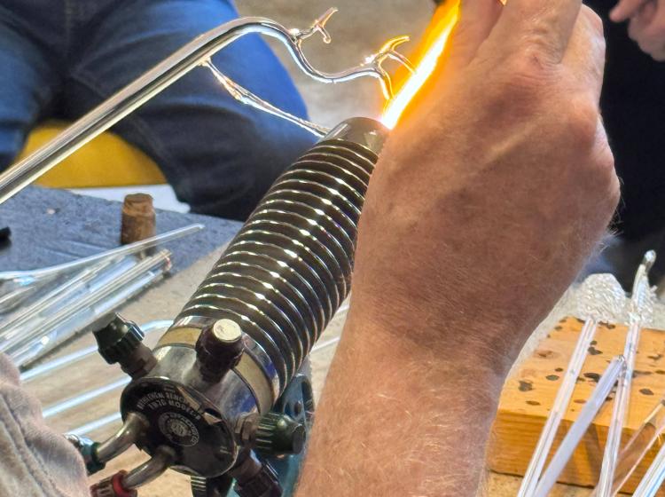 Student perspective shot as they use a torch on a branched piece of clear glass. 