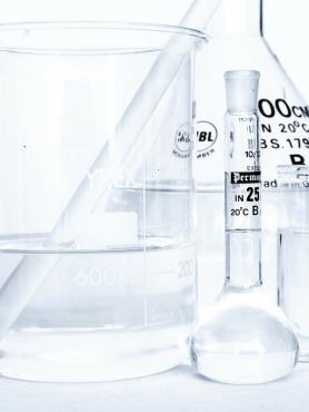 A group of glassware with clear liquid sit on a table.