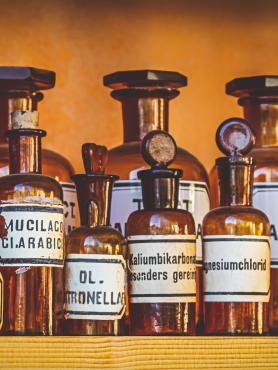 Old amber bottles with labels on them sit on a shelf. 