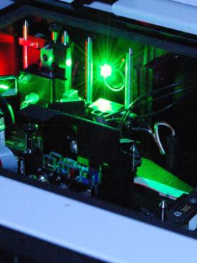 A green light shines in a compartment of a large scientific instrument. 