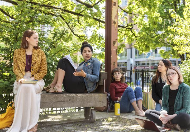 A group of students sit outside with notepads.