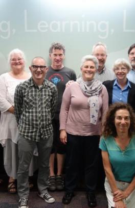 Faculty are seen standing in front of a blue wall