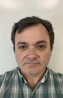 Paul Blakemore, a white man with short dark hair, is wearing a blue-grey flannel in front of a white background.