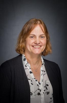 Robyn Tanguay, a white woman with chin-length red hair, is smiling in a professional headshot on a grey background. 