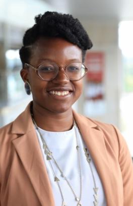 Lyniesha Ward, a black woman with short black hair and round glasses, smiling in front of a blurred background of an educational building.