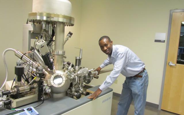 A person stands next to a large metal scientific instrument.