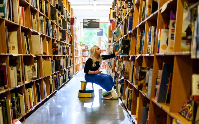 Woman selects a book from a large bookshelf.