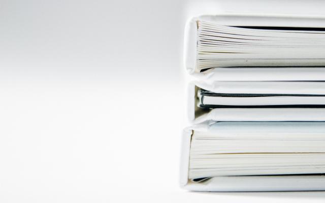 Three white binders or books are stacked.
