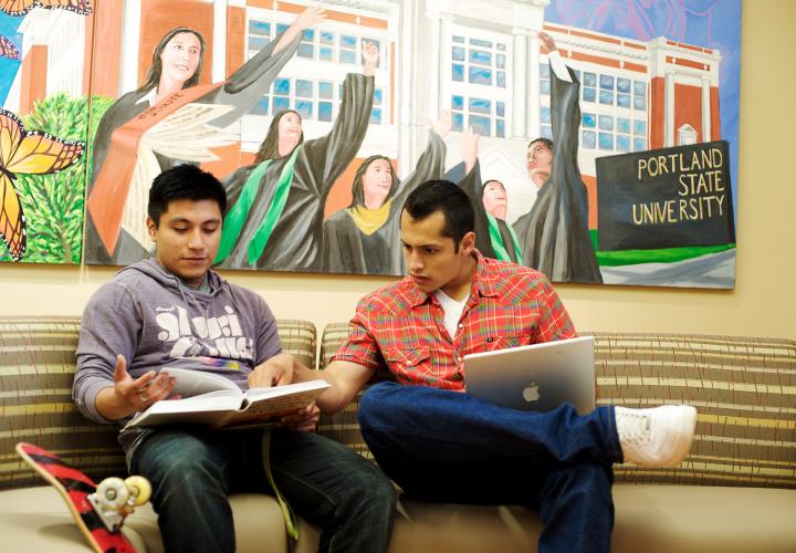 Two students studying together on couch with colorful mural in background