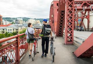 Two people walking bikes across a bridge