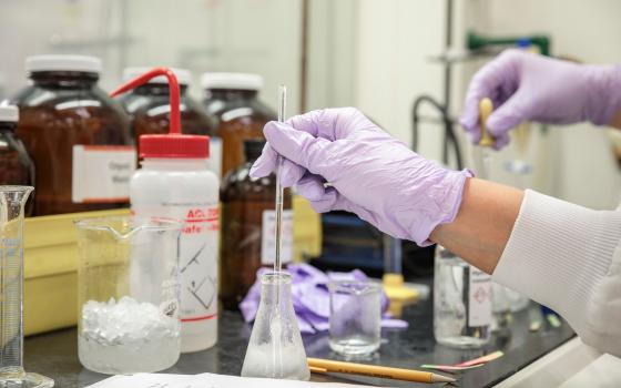 a gloved hand mixes a solution in a lab