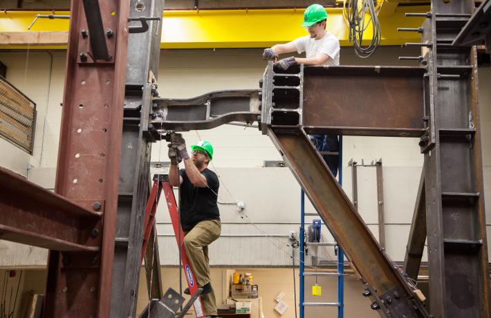 Two researchers working on a steel beam.