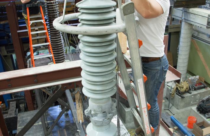 a researcher on a ladder, measuring a tall instrument