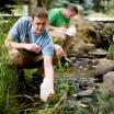 researchers collect water samples from a creek